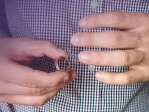 Homem de camisa xadrez tirando a aliança de casamento