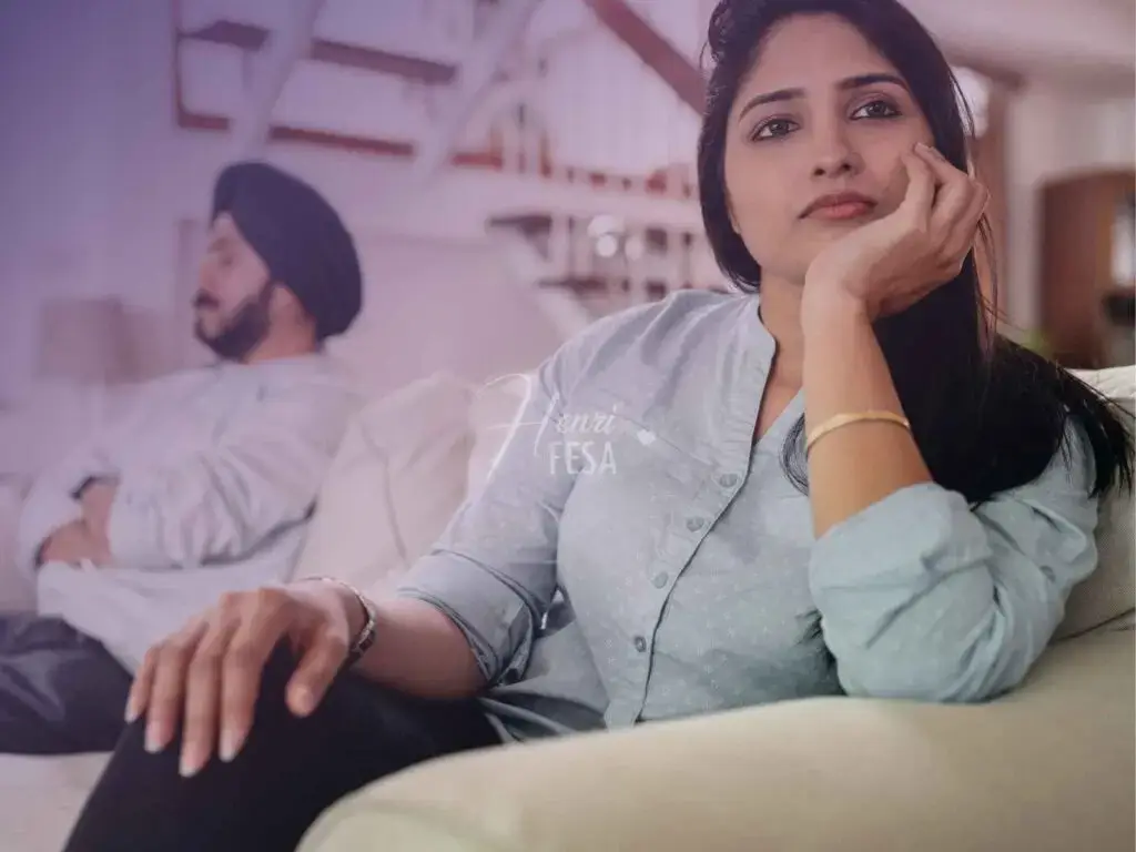 Homem sentado em uma extremidade do sofá com semblante sério e desconfortado enquanto a mulher está sentada na outra extremidade do sofá com semblantes preocupado e triste, provavelmente um casal em crise!