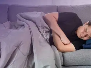 Homem dormindo no sofá com os braços cruzados e expressão de mágoa!