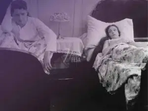 Mulher deitada em uma cama de casal pensativa e homem deitado em outra cama logo ao lado com ar de tristeza e preocupação, ambos separados por um móvel de cabeceira!