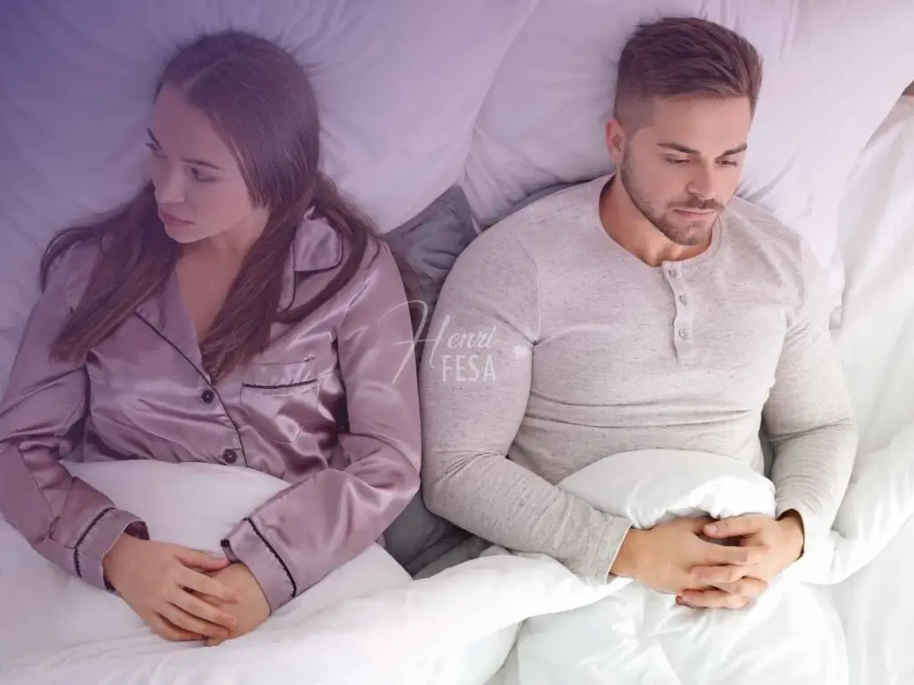 Casal homem e mulher deitados na cama, um de cada lado com tom de preocupação por conta do desgaste da relação!