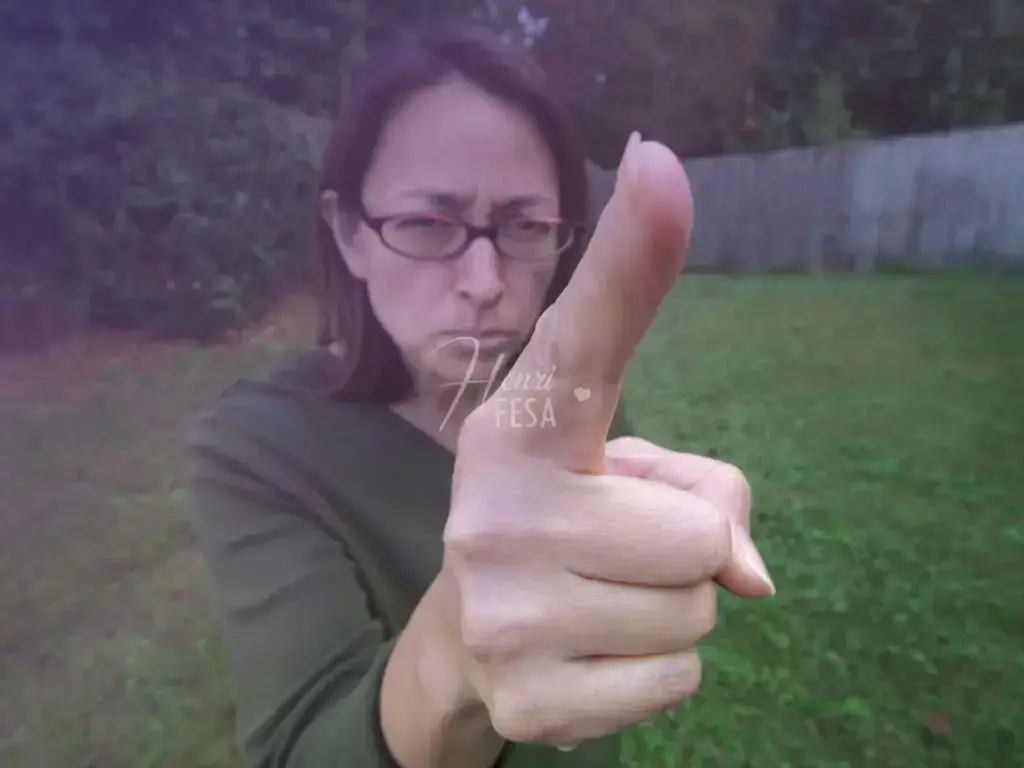 Mulher de óculos, casaco verde-escuro, apontando o dedo e expressando autoritarismo!