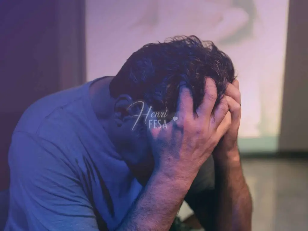 Homem, sentado com as mãos na cabeça, passando a ideia de reflexão profunda e tristeza após rejeição!