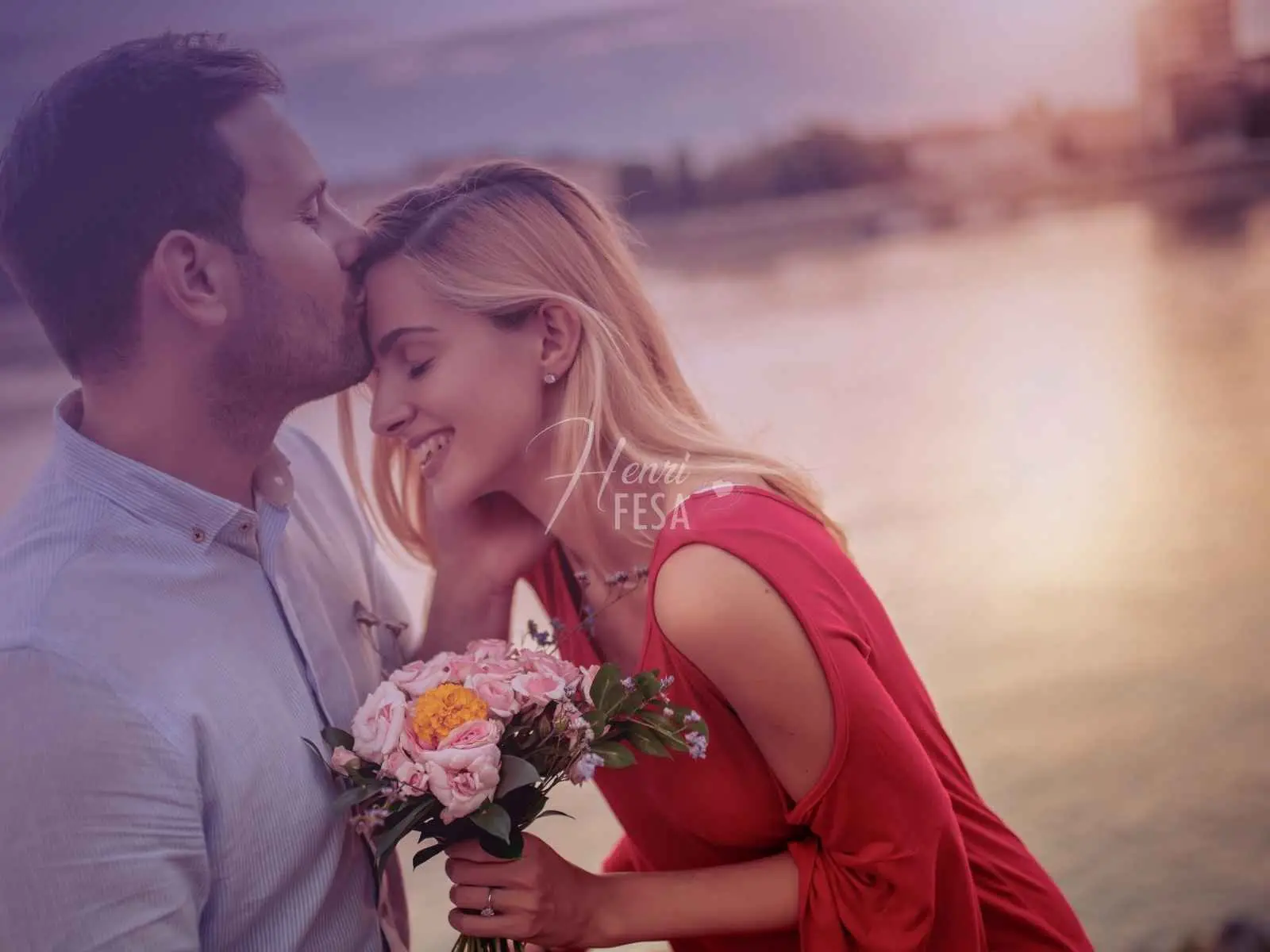 Casal se abraçando e se beijando na beira de um lindo lago ao pôr do sol!