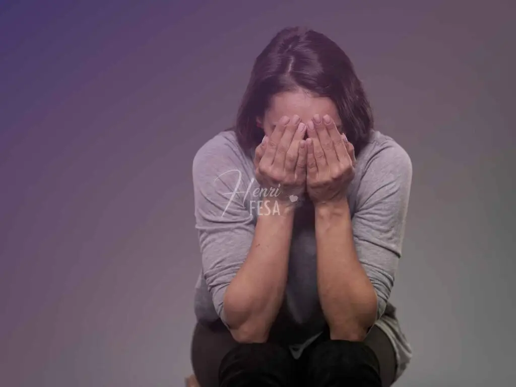 Mulher triste, com as mãos no rosto em tom de reflexão profunda por desânimo!