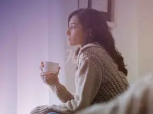 Mulher sentada no sofá e tomando uma xícara de café lentamente enquanto reflete se ele volta para ela!