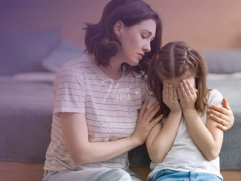 Mulher sentada ao sofá, abraçando a filha pequena que chora por conta da separação dos pais!