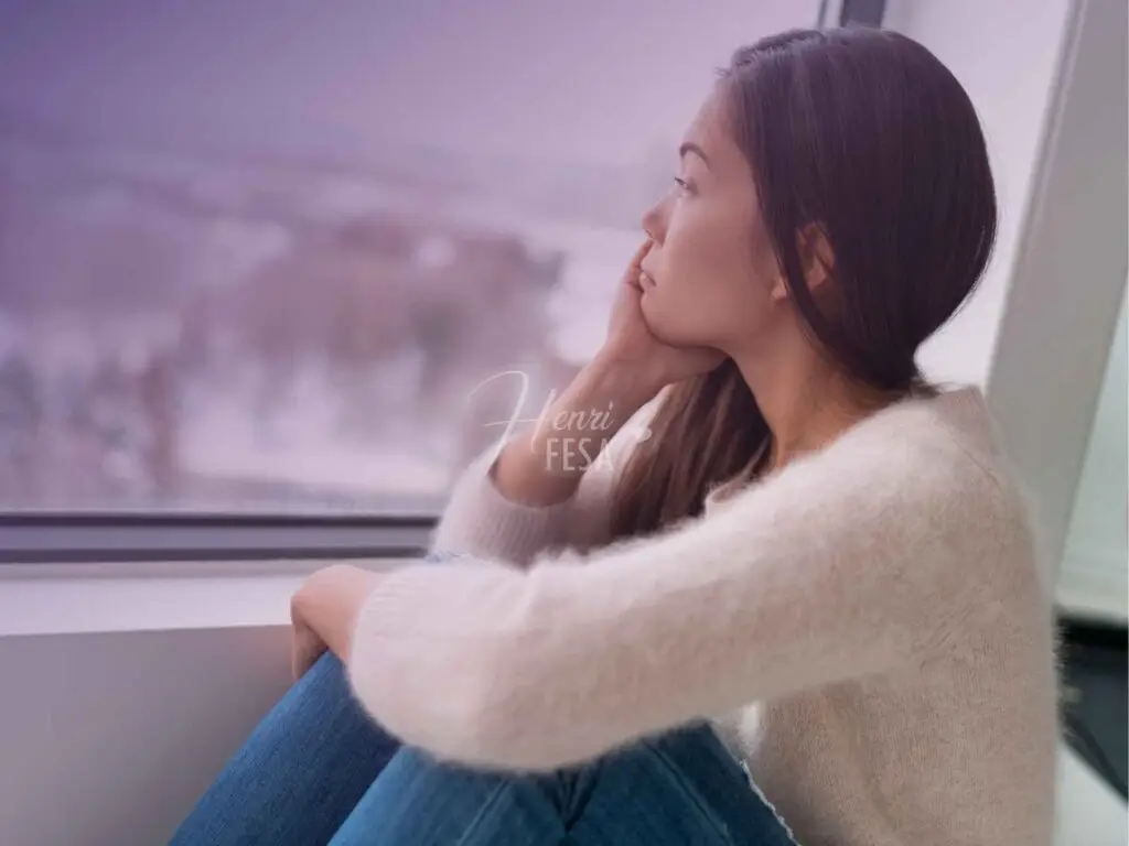 Mulher olhando pela janela e pensando de forma triste em tudo que não conquistou aos 30 anos!