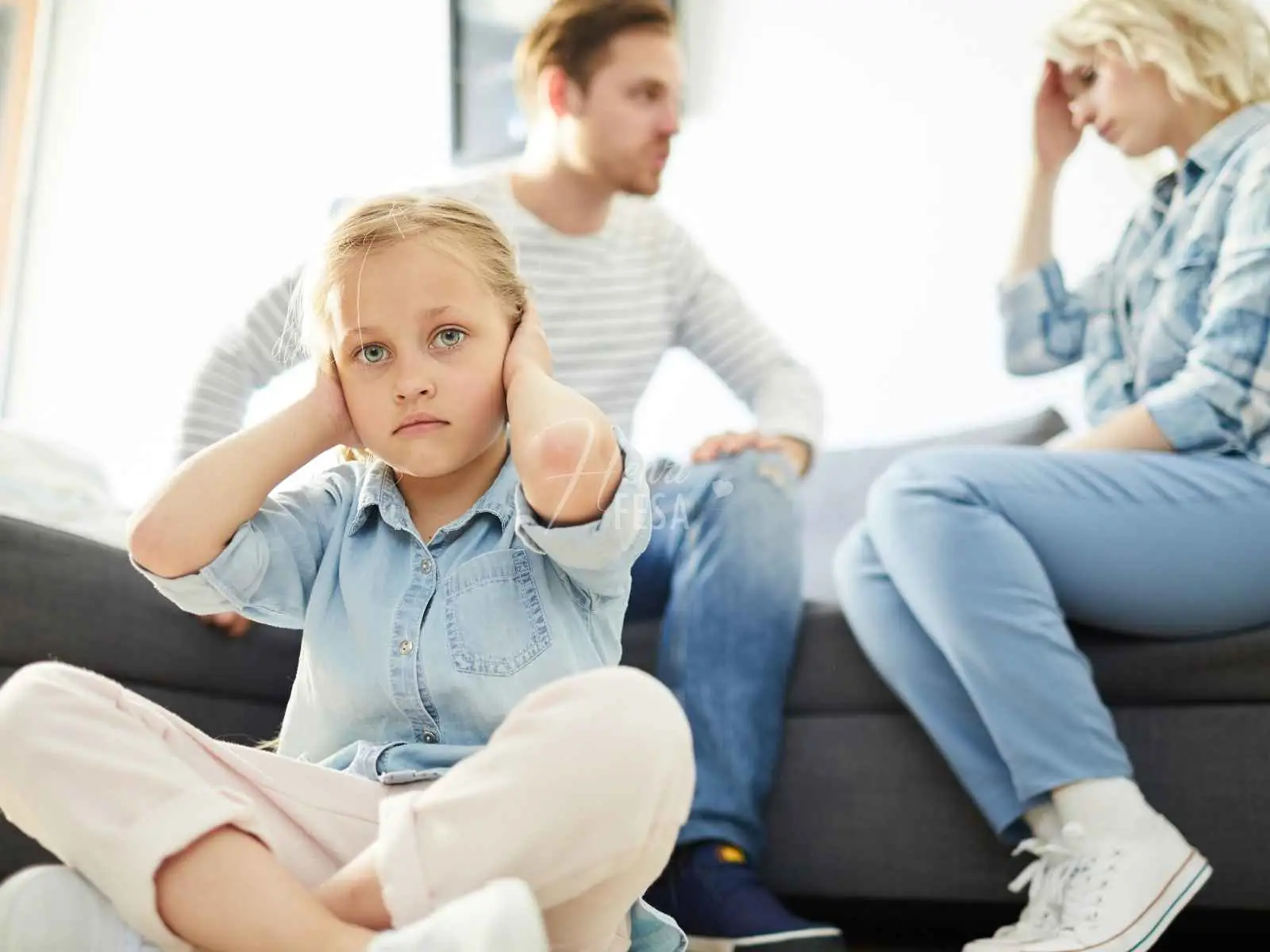 Casal homem e mulher discutindo no sofá, criança sentada chão da sala com as pernas cruzadas e com as mãos tampando os ouvidos, além de semblante de indignação!