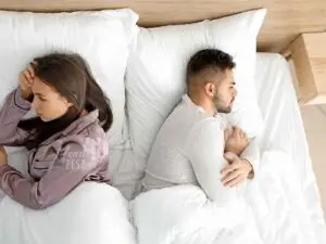 Casal homem e mulher deitados na cama, ambos de costas um para o outros e ambos com semblante de preocupação e conflito!