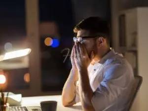 Homem exausta de trabalhar com as mãos no rosto em frente ao computador!