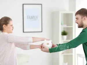 Mulher e homem brigando com um porquinho (cofrinho) em mãos, cada um puxando para o seu lado!