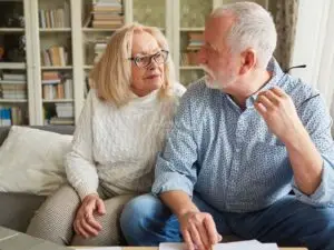 Homem e mulher 50+ conversando sobre finanças, ele impondo decisões, ela acuada olhando!
