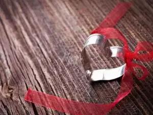 Um coração de metal com um laço vermelho amarrado, simbolizando a Amarração Amorosa com Oxum!