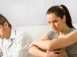 Esposa sentada ao sofá pensativa quando o marido fica emburrado e ela não sabe o que fazer!